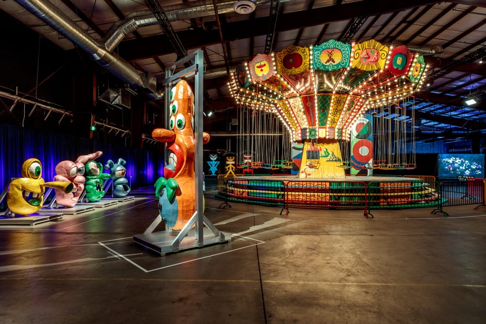 Colorful sculptures and a lit up carousel at the Luna Luna exhibit in LA