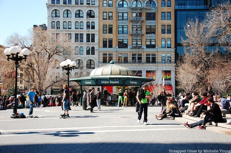 People mill about Union Square with the subway entrance and historic buildings in the background