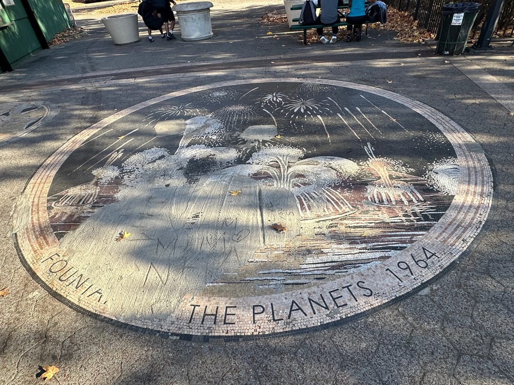 A mosaic on the ground that depicts Fountain of the Planets with a large cement patch covered in graffiti marks