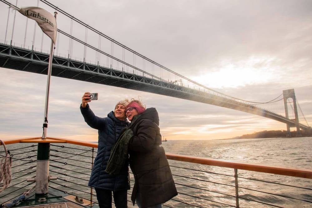 Two women take a selfie under the Verrazzano Bridge