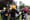 A man with a carved pumpkin on his head walks through a crowd of people in Halloween costumes at Socrates Sculpture Park.