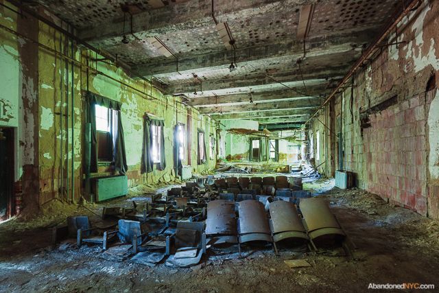 Green leaves and blue skies illuminate a crumbling auditorium in jewel tones.