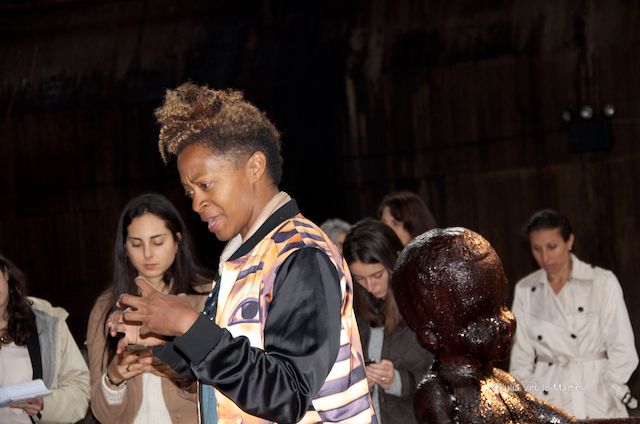 Kara Walker explaining her work beside boy of sugar