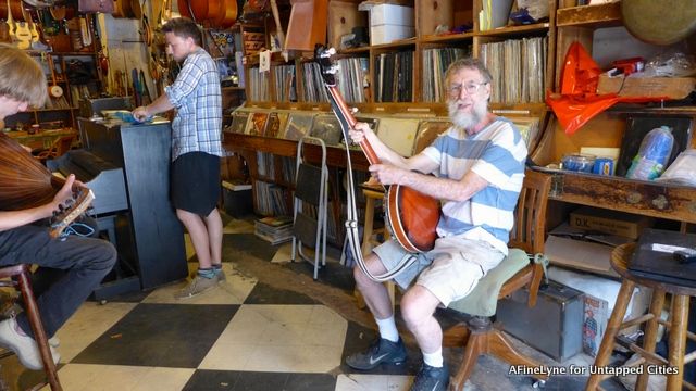 Jeff Slatnick, owner of The Music Inn holding an instrument just dropped off for repair