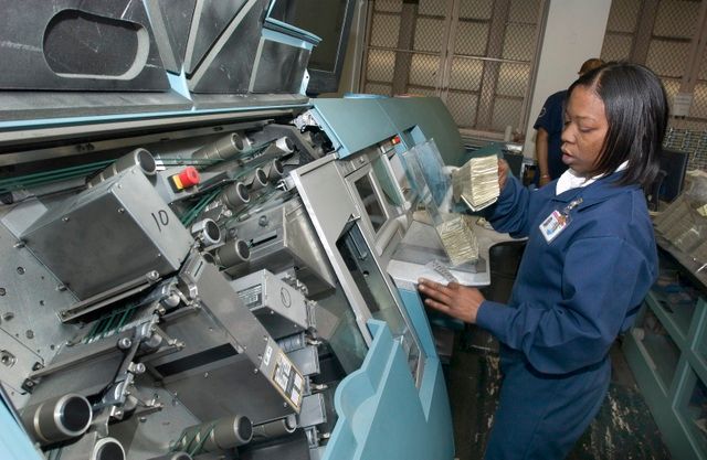 A woman uses a cash counting machine after collecting fares from the money train