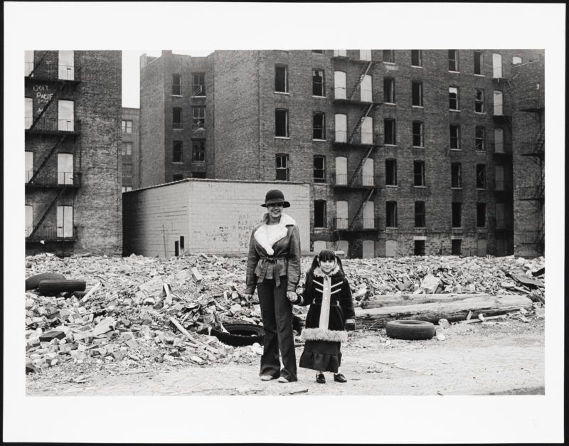 Mother and daughter pause in the ruins, which is still their hom