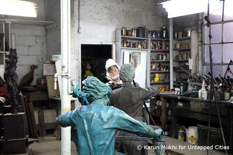 Using flames and chemicals, the sculpture being worked on will eventually share its color with the finished one in the foreground.