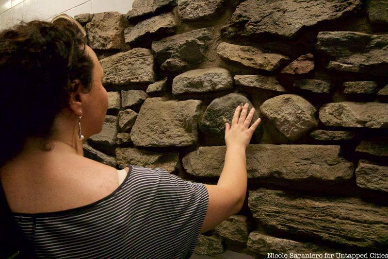 A tour guest touches an 18th century wall