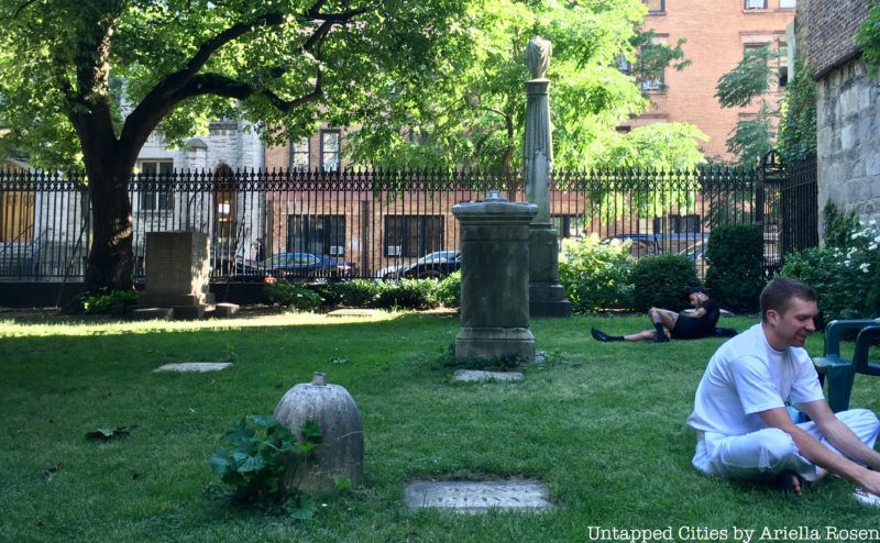 Two men lounge in the grass at New York City Marble Cemetery