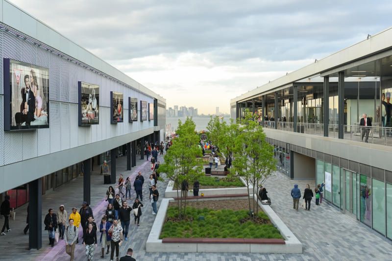 An overhead shot of the outdoor patio at Empire Outlets in Staten Island with the NYC skyline in the background