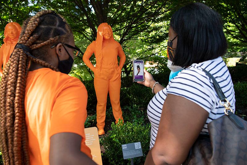 women looking at IfThenSheCan sculptures