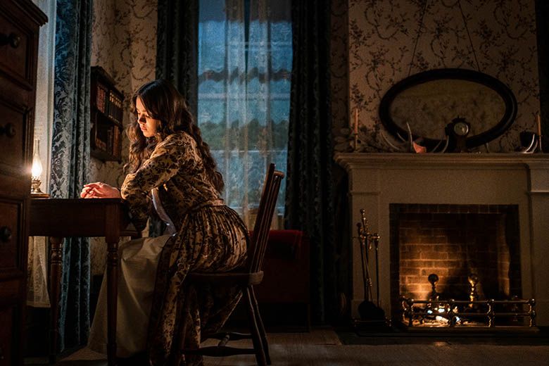 Emily Dickinson writing at her desk, played by Hailee Steinfeld