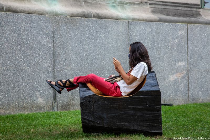 Woman seated in outdoor reading room at Brooklyn Public Library