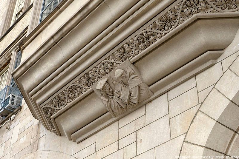 A carving of a priest and a scholar decorating a window of an Erasmus Hall building, March 2022.