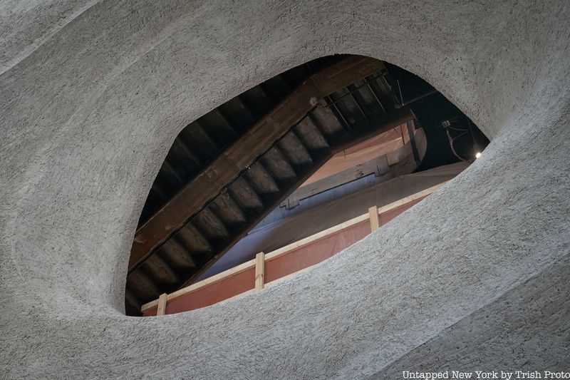 A hole carved out of shotcrete reveals the bottom of a staircase