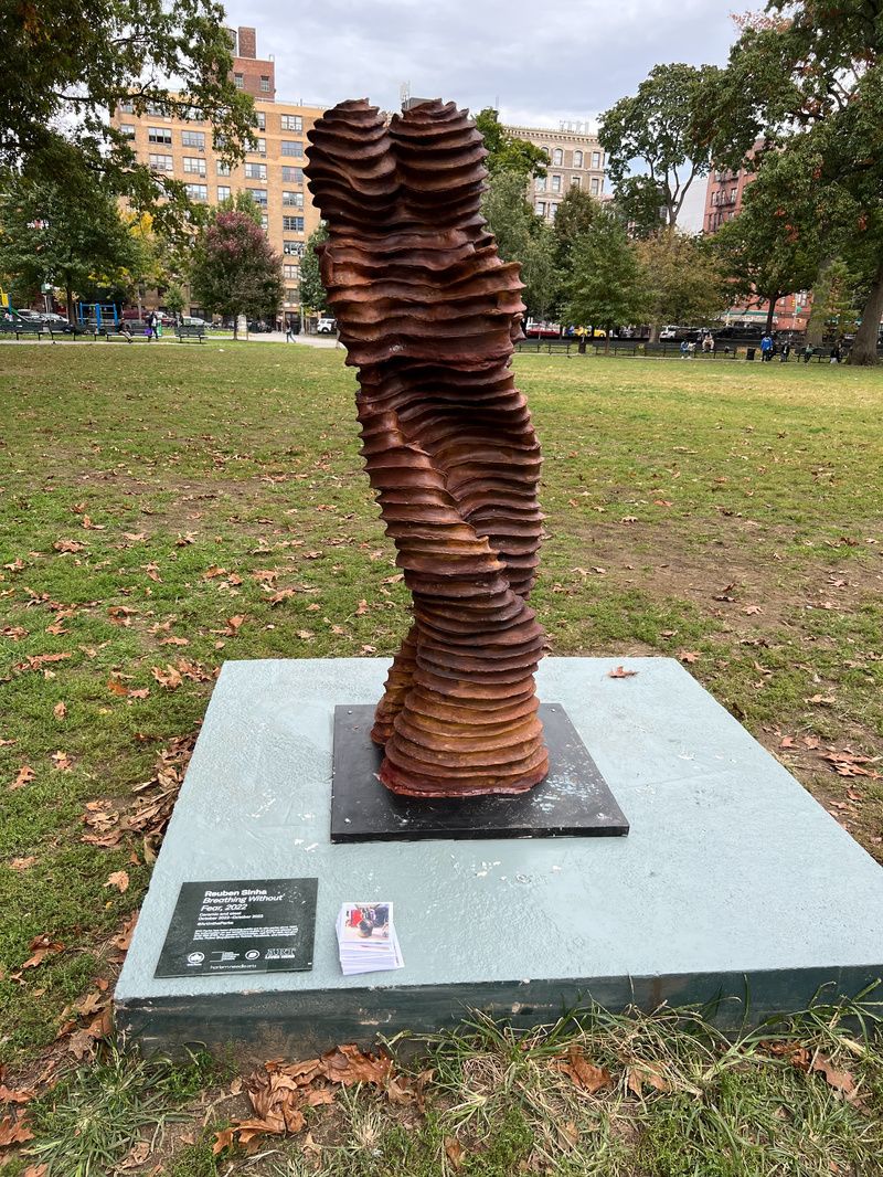 A brown ceramic sculpture of two intertwining figures at Marcus Garvey Park