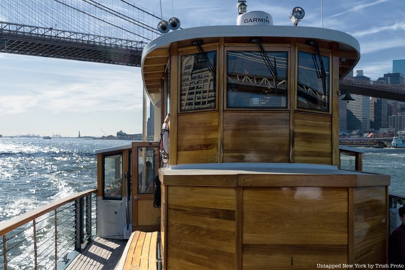 The front of a boat as it passes under a bridge in NYC