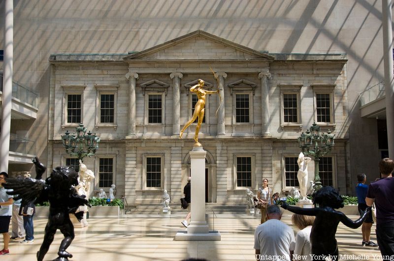 A gold statue stands at the center of the American Wing at the Metropolitan Museum of Art