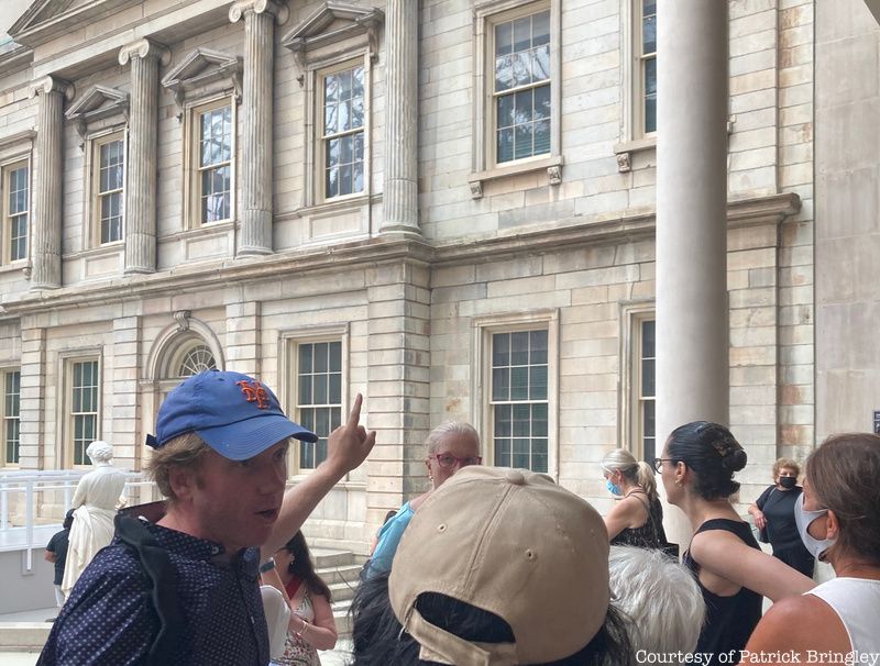 Tour guide Patrick Bringley points to architectural features of the Met in front of a group of tourgoers.