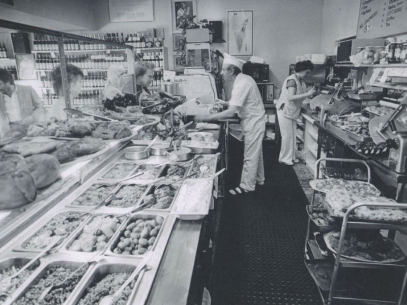 A deli worker serves customers at the counter of a jewish deli in 1970s Hollywood.