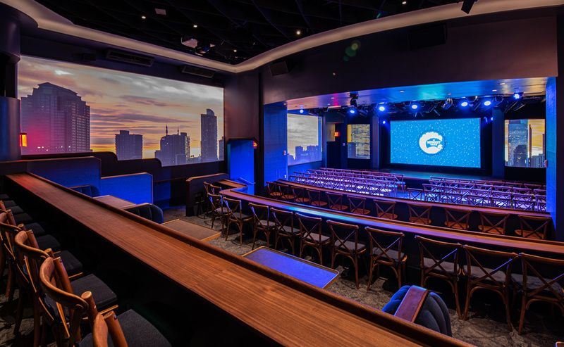 Screens inside NYC's Midnight Theatre project a city skyline next to rows of audience chairs