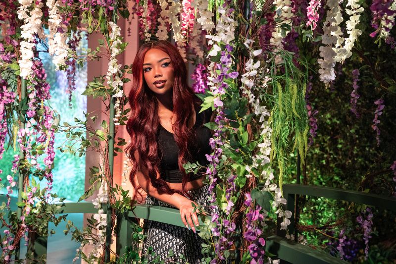 A woman peeks through hanging flowers at Monet's Garden