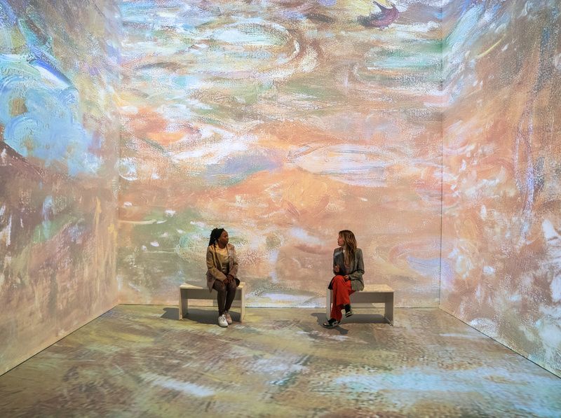 Two people sit on a bench at Monet's Garden Immersive Experience