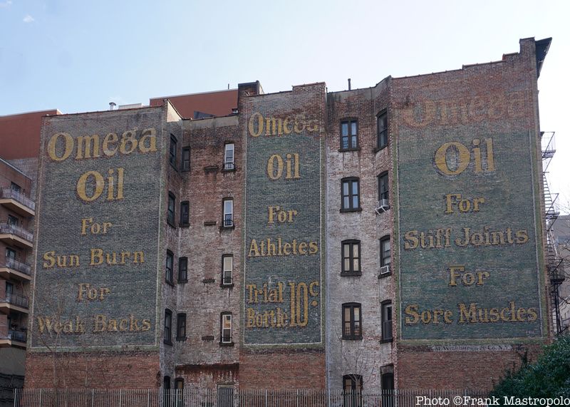 Three Omega Oil painted ghost signs on the side of a brick building