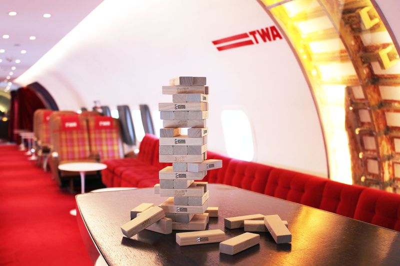 A stack of JENGA blocks on a. table inside the airplane bar at TWA Hotel