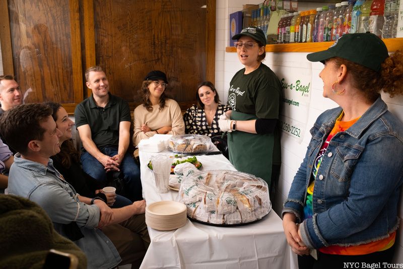 A group of people sitting around a table covered in bagel samples for an NYC Bagel Tour