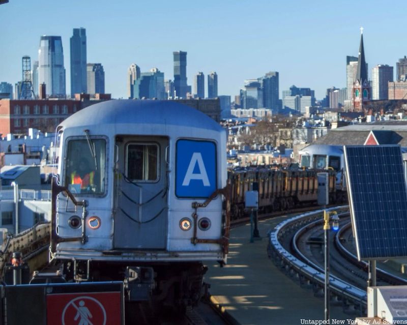 A silver subway car pulling barrels full of garbage