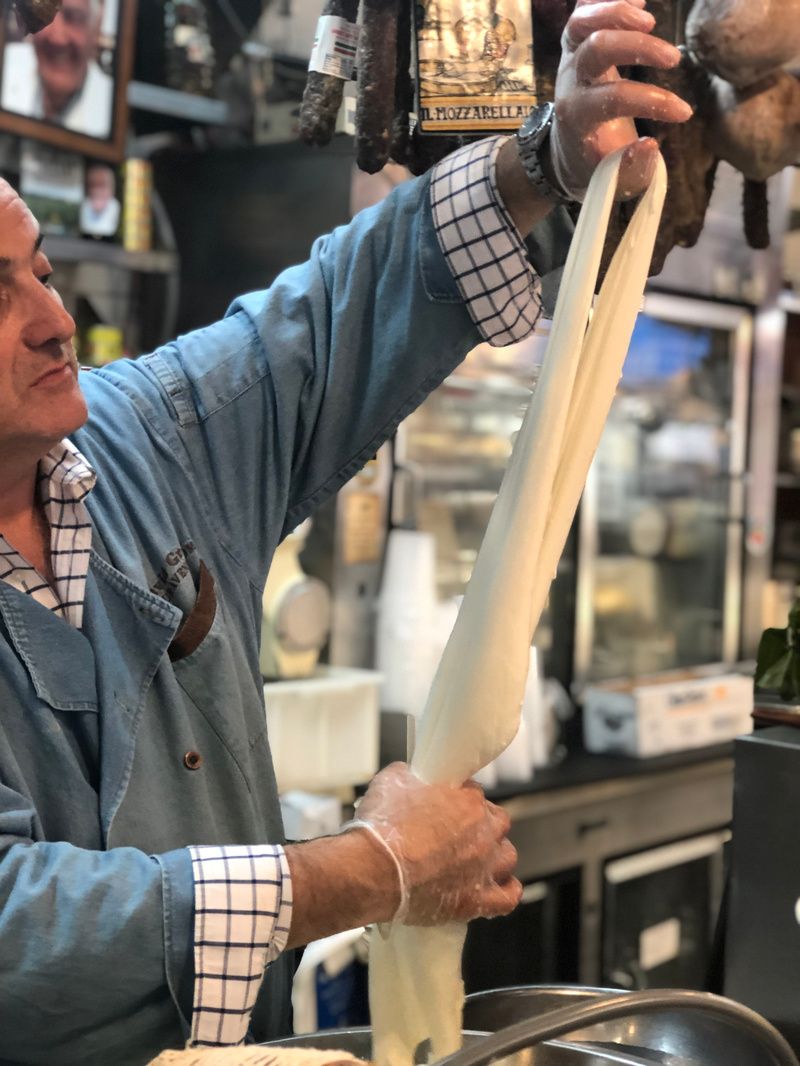 A man stretches a piece of mozzarella