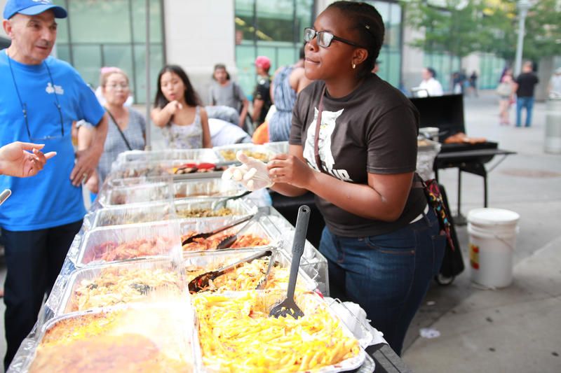 A women stands behind a table full of food trays