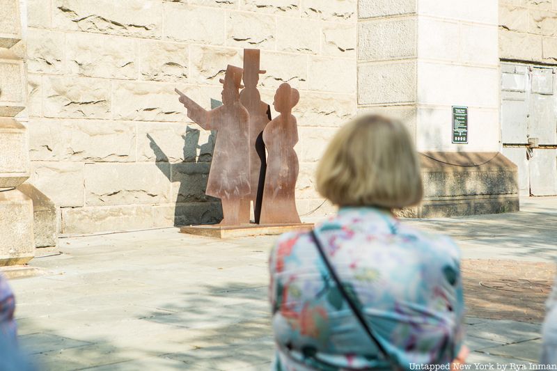 A woman looks at the sculpture of Emily Roebling, Washington and John