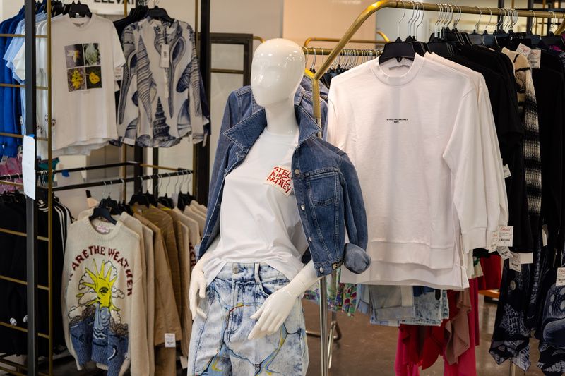 A mannequin stands in front of clothing racks