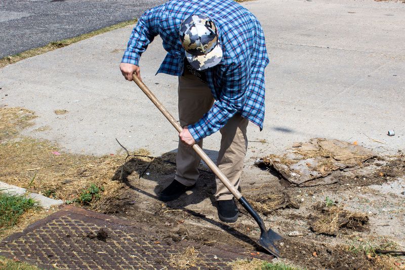 New Orleans Sewage and Water boy cleaning out a storm drain with a shovel