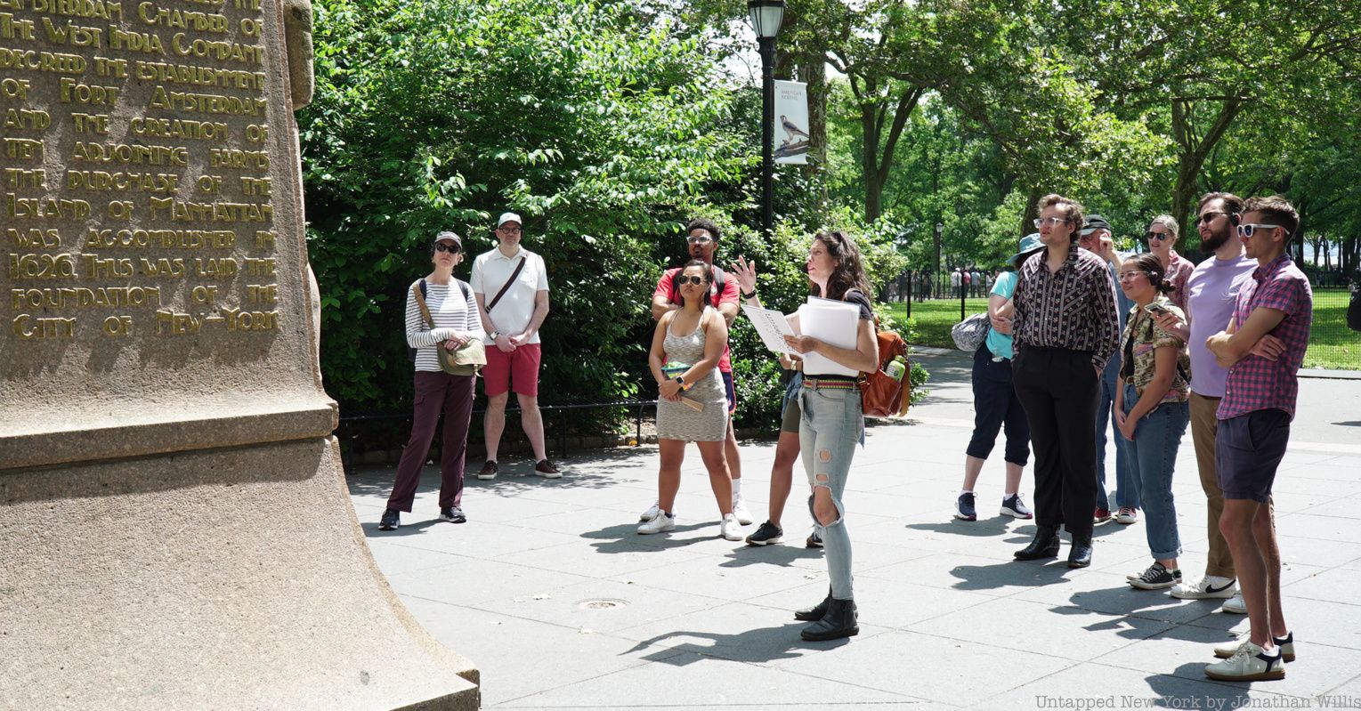 Tourgoers on a Remnants of Dutch New Amsterdam tour touch a stone wall in the subway