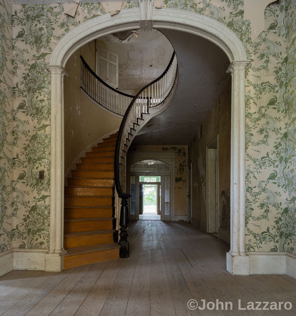 Staircase framed by an arched opening in.a wall covered in wallpaper