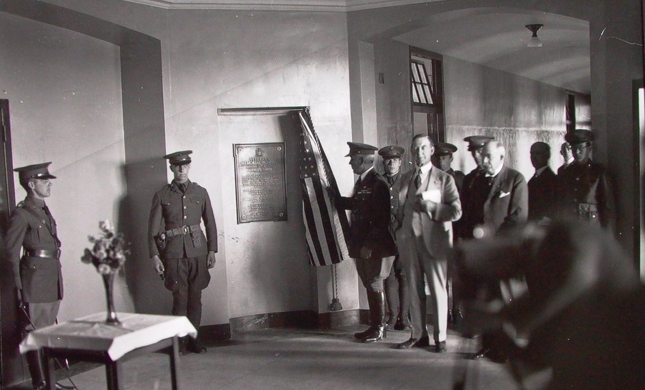 Military personnel and men in suits present a plague at Kings Park