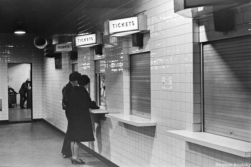 A couple stands at a train station ticket booth