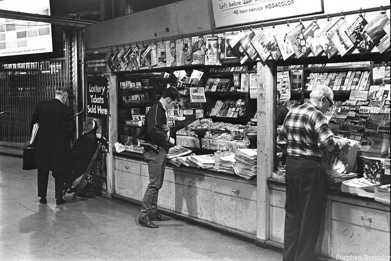 People stand at a newstand in an LIRR station