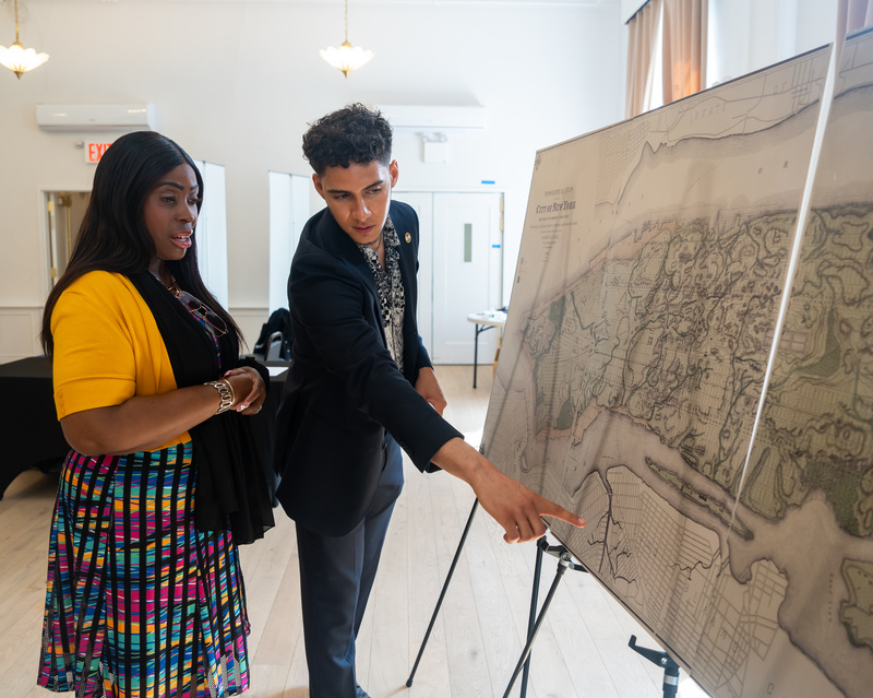 Two people point at a map of Manhatta