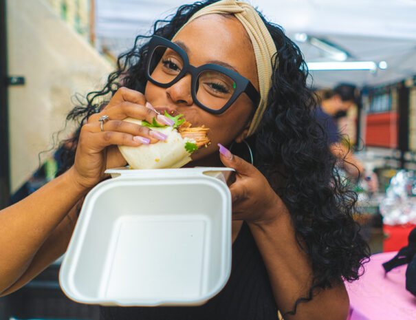 Woman bites into food at the Brooklyn Night Market