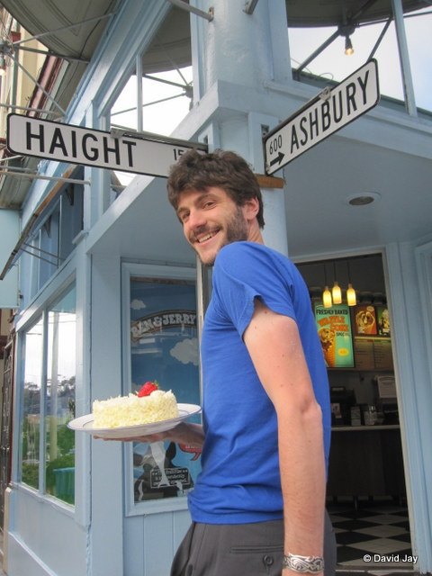Asexual David Jay at the corner of Haight and Ashbury with a slice of cake with white frosting and a little strawberry on top, symbolizing celebration, the asexual community’s answer to the LGBT rainbow.