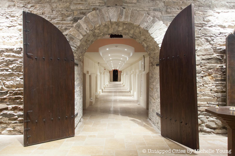 Large wooden doors open to the long hallway of the crypt beneath the Basilica of St. Patrick's Old Cathedral.