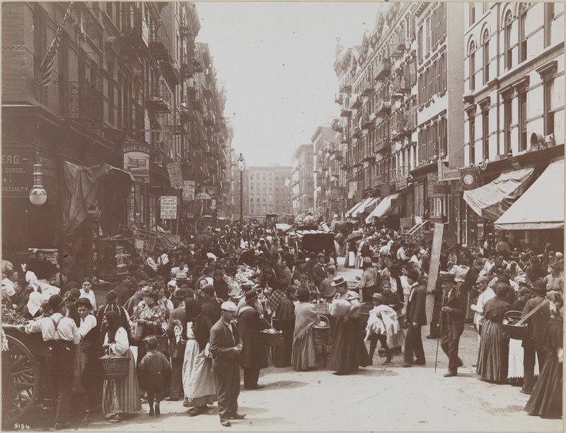 A crowd of people on Orchard Street, lined with street vendors.
