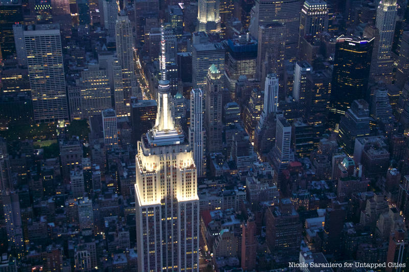 The top of the Empire State building glows with white lights.