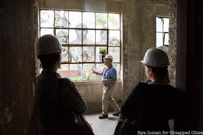 Guests in hard hats listen to a guide on the behind-the-scenes Ellis Island abandoned hospital tour