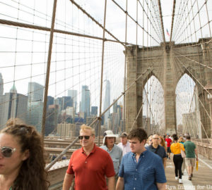 Group of tourgoers walking across the Brooklyn Bridge