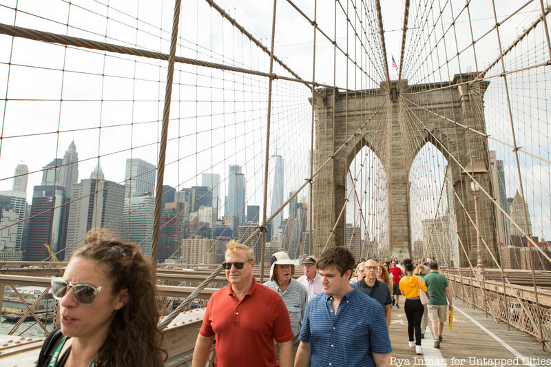 Group of tourgoers walking across the Brooklyn Bridge